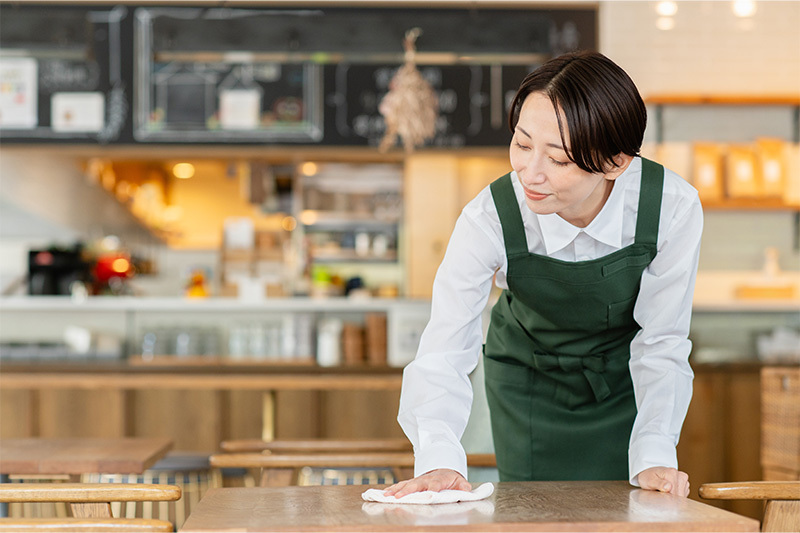 カフェでテーブルを拭く女性