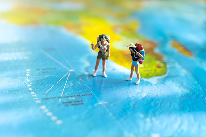 地球儀の上にいるバックパッカー男女のミニチュア